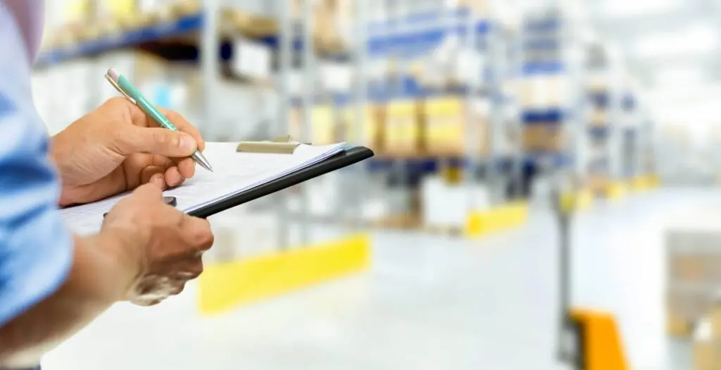Person writing on a clipboard in warehouse